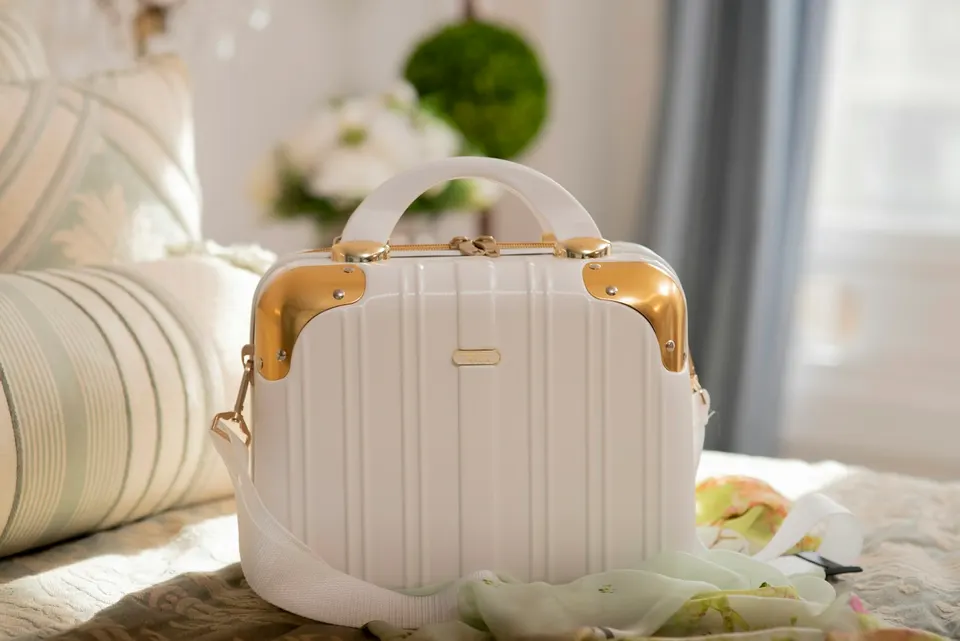 A cream travel case on a bed in a bright room.