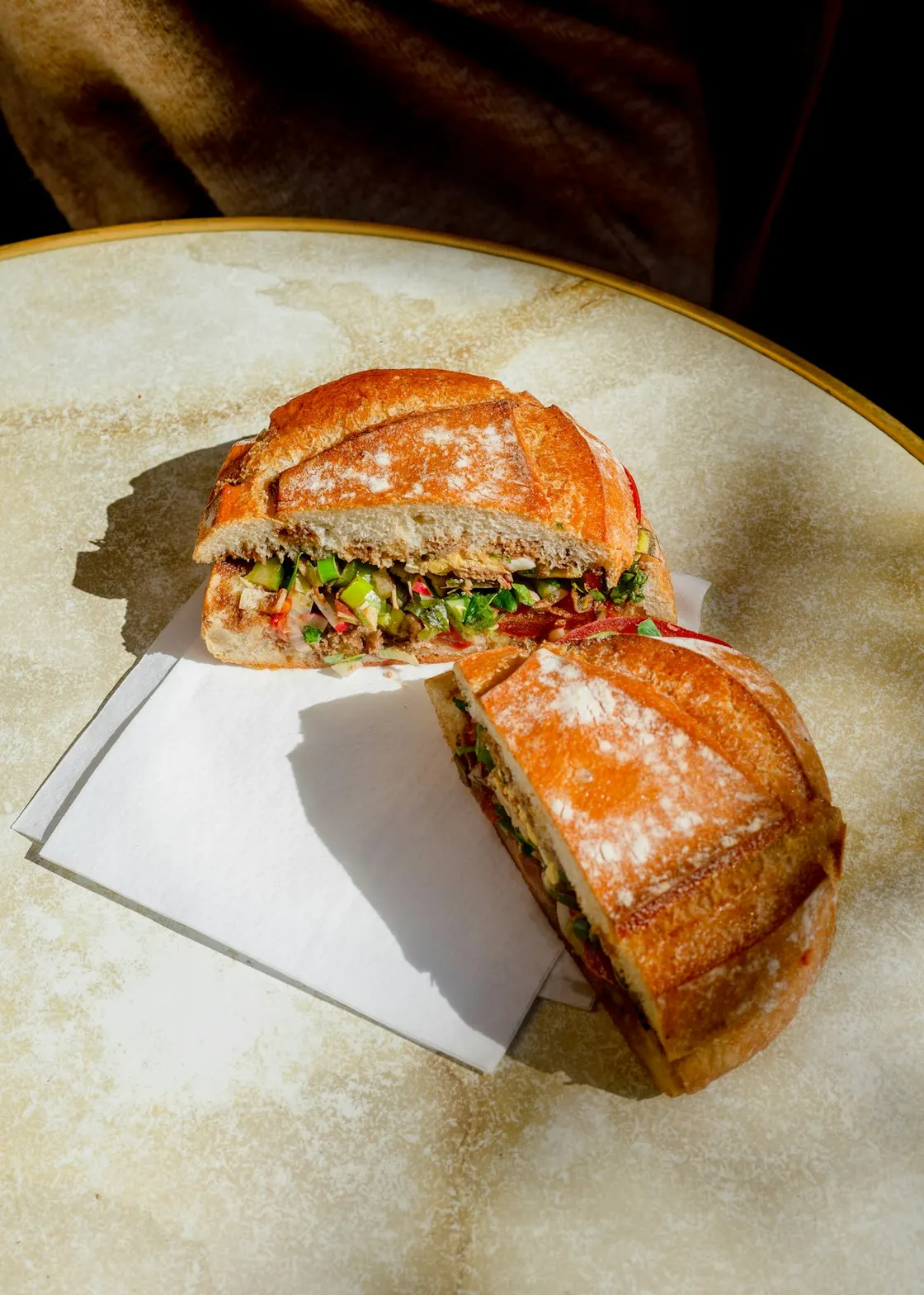 Two halves of a filled sandwich on paper on a table.