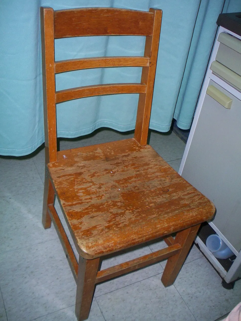 An empty wooden chair with a ladder-style back and four fixed legs.